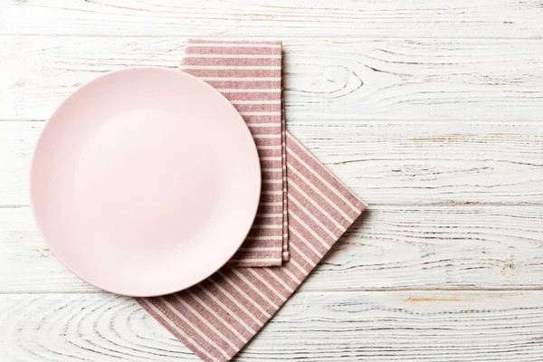 食べ物のためのテーブルクロス上の色の背景の空のラウンドピンクのプレートの上のビュー あなたのデザインのためのスペースとナプキンに空の料理 — ストック写真