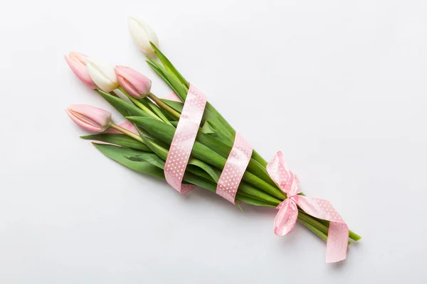 Bouquet of pink tulips on colored table background . Top view with copy space. Waiting for spring. Happy Easter card. Flat lay.