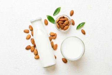 Cam şişedeki badem sütü ve renkli masada badem fıstığı. Üst görünüm vith kopyalama alanı.