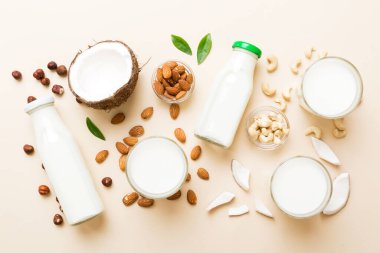 Masa arkasında çeşitli vejetaryen süt bademi, hindistan cevizi, fındık. Vejetaryen bitkisi sütü ve malzemeleri, üst görünüm.