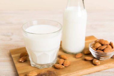 Cam şişedeki badem sütü ve renkli masada badem fıstığı. Üst görünüm vith kopyalama alanı.