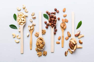 mixed nuts in white wooden spoon. Mix of various nuts on colored background. pistachios, cashews, walnuts, hazelnuts, peanuts and brazil nuts.