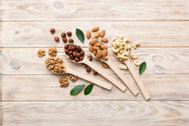 mixed nuts in white wooden spoon. Mix of various nuts on colored background. pistachios, cashews, walnuts, hazelnuts, peanuts and brazil nuts.