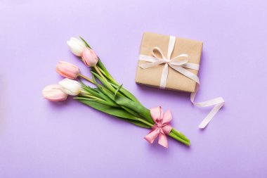 Pembe lale çiçekleri ve hediye ya da renkli masa arkaplanındaki hediye kutusu. Anneler günü, doğum günü, kadınlar günü, kutlama konsepti. Metin üstü görünümü için boşluk.
