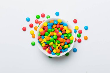 Renkli arka planda bir kasede çok renkli şekerler. Doğum günü ve tatil konsepti. Kopyalama alanı olan üst görünüm.