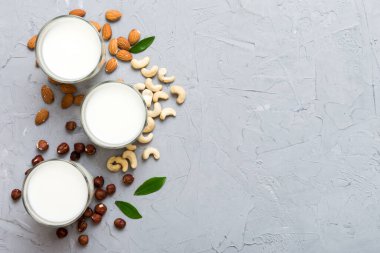 Masa arkasında çeşitli vejetaryen süt bademi, kaju fıstığı seti ya da koleksiyonu. Vejetaryen bitkisi sütü ve malzemeleri, üst görünüm.