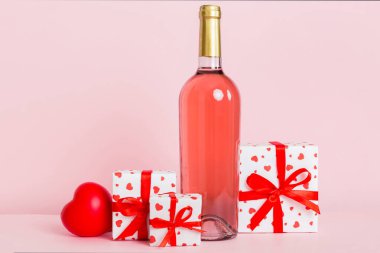 Bottle of wine on colored background for Valentine Day with gift box. Heart shaped with presrnt box perspective view with copy space.