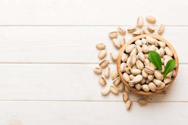 Fresh healthy Pistachios in bowl on colored table background. Top view. Healthy eating concept. Super foods.