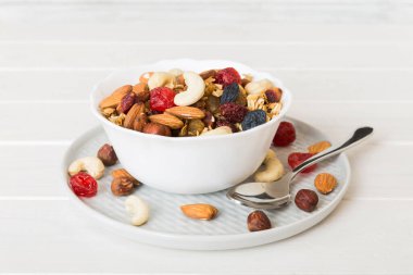 Sağlıklı bir kahvaltı hazırlıyorum. Bir kasede çeşitli kurutulmuş meyve ve fındıklı granola. Sağlıklı tatlı kavramı. Düz konum, kopyalama alanı olan üst görünüm.