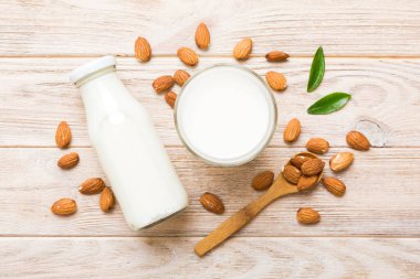 Cam şişedeki badem sütü ve renkli masada badem fıstığı. Üst görünüm vith kopyalama alanı.