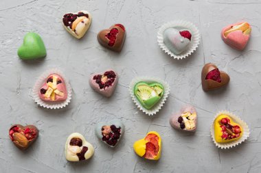 chocolate sweets in the form of a heart with fruits and nuts on a colored background. top view with space for text, holiday concept.