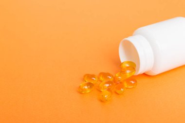 Omega-3 kapsülleri masa arkasında beyaz bir şişede yatıyor. Balık yağı tabletlerinin üst görüntüsü. Biyolojik olarak aktif katkı maddeleri. omega 6, omega 9, A vitamini, D vitamini, D3 vitamini, akşam çuha çiçeği yağı.