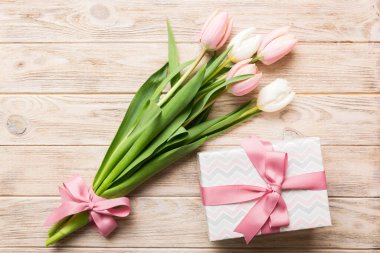 Pembe lale çiçekleri ve hediye ya da renkli masa arkaplanındaki hediye kutusu. Anneler günü, doğum günü, kadınlar günü, kutlama konsepti. Metin üstü görünümü için boşluk.
