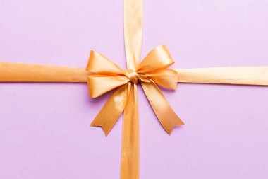 Altın kurdelenin üst görüntüsü yuvarlandı ve sarı fiyonk renkli arka planda izole edildi. Kopyalama alanı olan düz.