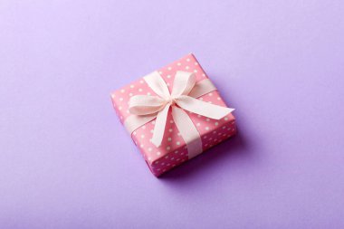 Noel 'i ya da diğer tatil hediyelerini renkli arka planda kurdeleyle renkli kağıda sardım. Şimdiki kutu, renkli tabloda hediye süslemesi, kopya alanı ile üst görünüm.