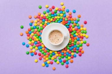 Coffee cup with chocolates and colored candy. Top view on table background with copy space.