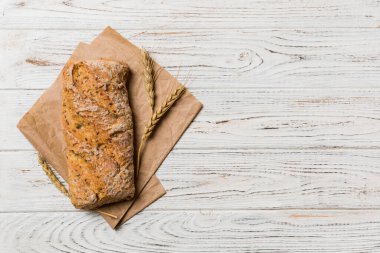 Renkli bir masada buğday ve glüten ile taze somunlar. Peçetedeki ekmek kırsal arka planda, taze ekmek üst görünümü.