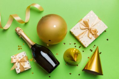 Renkli arka planda şampanya şişesi hediye paketi kurdeleleri ve konfetilerin düz kompozisyonu vardı. Düz konum, üst görünüm tatil konsepti.