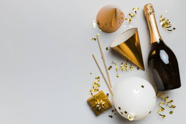Renkli arka planda şampanya şişesi hediye paketi kurdeleleri ve konfetilerin düz kompozisyonu vardı. Düz konum, üst görünüm tatil konsepti.