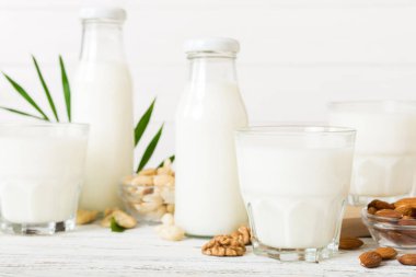 Masa arkasında çeşitli vejetaryen süt bademi, kaju fıstığı seti ya da koleksiyonu. Vejetaryen bitkisi sütü ve malzemeleri, üst görünüm.