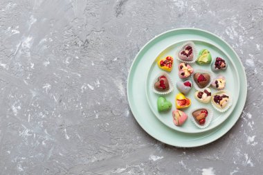 Plate with different chocolate on colored background. Assortment of fine chocolates top view vith copy space Health and obesity concept.