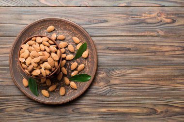 Fresh healthy Almond in bowl on colored table background. Top view.