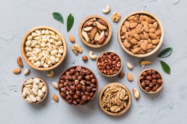 mixed nuts in wooden bowl. Mix of various nuts on colored background. pistachios, cashews, walnuts, hazelnuts, peanuts and brazil nuts.