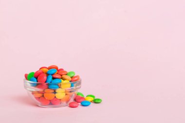 Renkli arka planda bir kasede çok renkli şekerler. Doğum günü ve tatil konsepti. Kopyalama alanı olan üst görünüm.