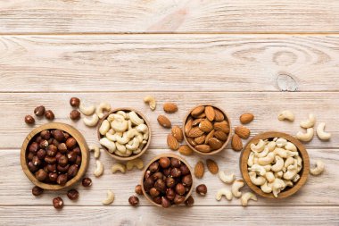 Renkli masadaki ahşap kasede fındık çeşitleri. Ceviz, fındık, ceviz, badem. Fındık Üst görünümü ile kopyalama alanını karıştır.