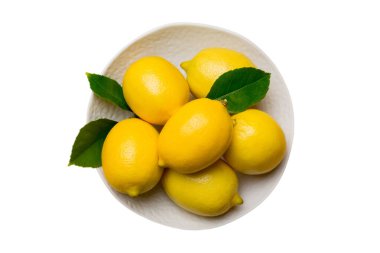 Taze kesilmiş limon ve beyaz arka planda izole edilmiş yuvarlak tabağın üzerindeki bütün limonlar. Yemek ve içecek malzemeleri hazırlanıyor. Sağlıklı beslenme tema üst görünümü kopyalama alanı ile.