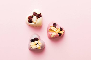 chocolate sweets in the form of a heart with fruits and nuts on a colored background. top view with space for text, holiday concept.