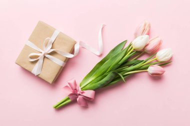 Pembe lale çiçekleri ve hediye ya da renkli masa arkaplanındaki hediye kutusu. Anneler günü, doğum günü, kadınlar günü, kutlama konsepti. Metin üstü görünümü için boşluk.