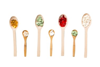 Renkli arka planda tahta kaşıkta vitamin ve mineral haplarının üst görünümü. Muhtelif ilaç haplarının en üst görüntüsü. Beslenme takviyesi sağlık ürünleri.