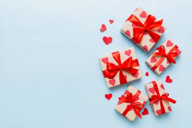 Top view photo of valentine day decorations gift box with red ribbon bow on colored background. Holiday gift boxes with top view.
