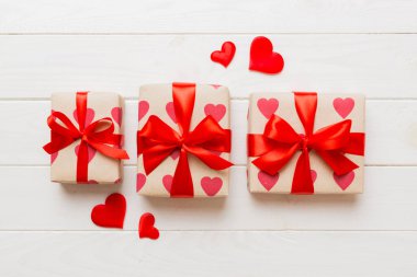 Top view photo of valentine day decorations gift box with red ribbon bow on colored background. Holiday gift boxes with top view.