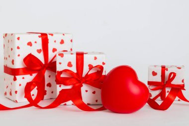 gift box with red bow and red heart on colored background. Perspective view. Flat lay.