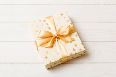 Noel 'i ya da diğer tatil hediyelerini renkli arka planda altın kurdeleli beyaz kağıda sardım. Şimdiki kutu, renkli tabloda hediye süslemesi, kopya alanı ile üst görünüm.