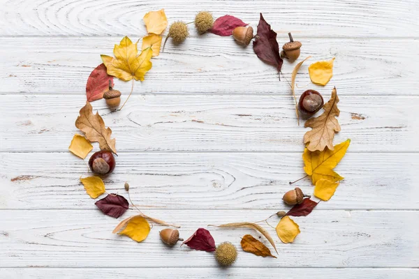 Masadaki kurumuş yapraklar, koniler ve meşe palamutlarından oluşan sonbahar kompozisyonu. Düz yatış, üst görünüm.