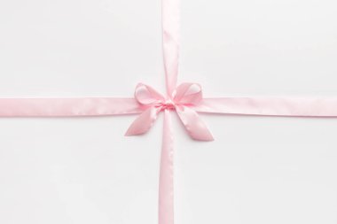 Mor kurdelenin üst görüntüsü yuvarlandı ve pembe fiyonk renkli arka planda izole edildi. Kopyalama alanı olan düz.