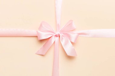 Mor kurdelenin üst görüntüsü yuvarlandı ve pembe fiyonk renkli arka planda izole edildi. Kopyalama alanı olan düz.