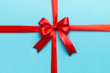 Kırmızı kurdelenin üst görüntüsü yuvarlandı ve kırmızı fiyonk renkli arka planda izole edildi. Kopyalama alanı olan düz.