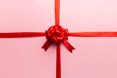 Kırmızı kurdelenin üst görüntüsü yuvarlandı ve kırmızı fiyonk renkli arka planda izole edildi. Kopyalama alanı olan düz.