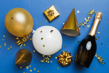 Renkli arka planda şampanya şişesi hediye paketi kurdeleleri ve konfetilerin düz kompozisyonu vardı. Düz konum, üst görünüm tatil konsepti.