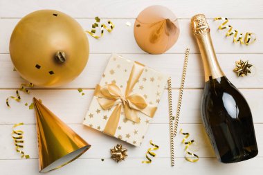 Renkli arka planda şampanya şişesi hediye paketi kurdeleleri ve konfetilerin düz kompozisyonu vardı. Düz konum, üst görünüm tatil konsepti.