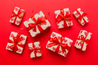 Top view photo of valentine day decorations gift box with red ribbon bow on colored background. Holiday gift boxes with top view.