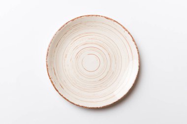 Renkli arka plan görüntüsünün üst görüntüsü yiyecek için boş, yuvarlak bej bir tabak. Tasarımınız için alanı olan boş tabak.
