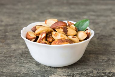 Fresh healthy Brazil nuts in bowl on colored table background. Top view Healthy eating bertholletia concept. Super foods.