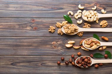 mixed nuts in white wooden spoon. Mix of various nuts on colored background. pistachios, cashews, walnuts, hazelnuts, peanuts and brazil nuts.