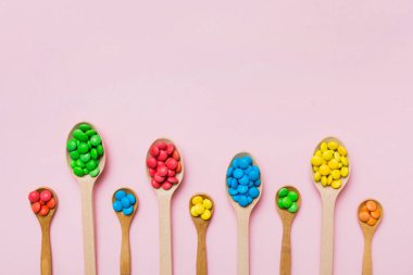 Renkli arka planda kaşık üzerinde renkli tatlı şekerler. Fotokopi alanı ile şekerleme dekoru üst görünümü.