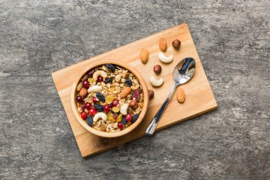 Sağlıklı bir kahvaltı hazırlıyorum. Bir kasede çeşitli kurutulmuş meyve ve fındıklı granola. Sağlıklı tatlı kavramı. Düz konum, kopyalama alanı olan üst görünüm.